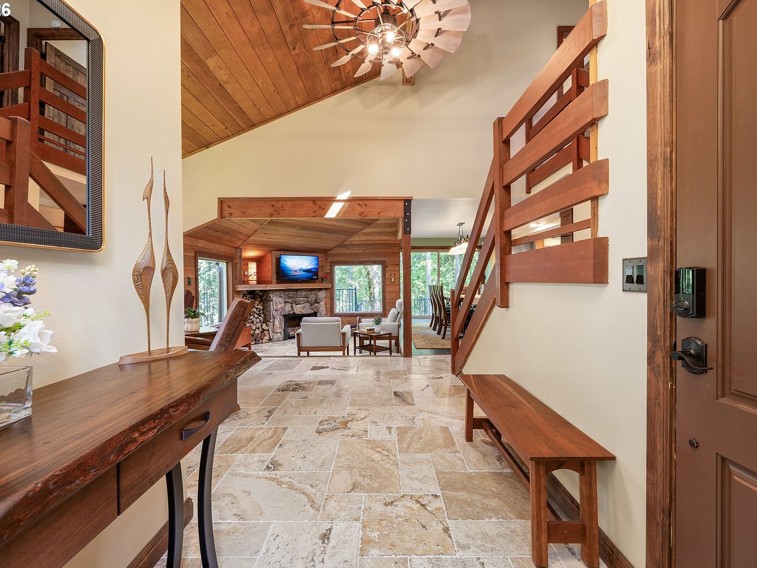 Foyer at 4330 N Shasta Loop, with wide-format Italian Luna travertine floor flowing into the great room, a wood-clad vaulted ceiling overhead, and a river-stone fireplace beyond